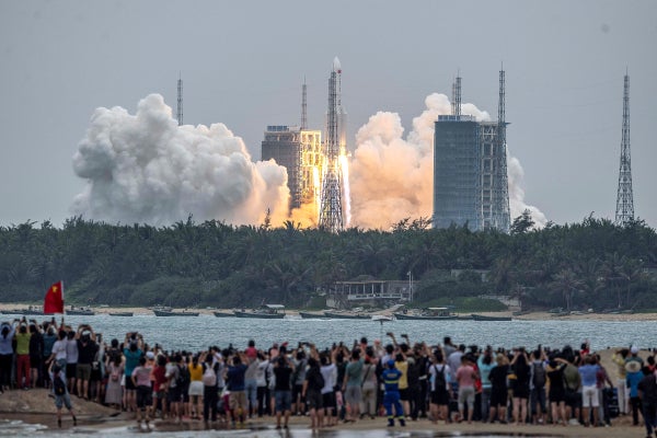 People watch a rocket carrying China's Tianhe space station core module, as it lifts off from the Wenchang Space Launch Center.