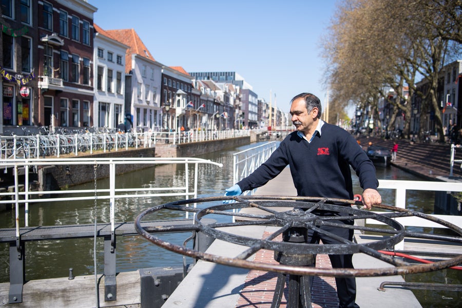 Man holding mechanical wheel which opens boat lock