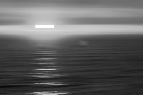 A blurred white light hovers over the ocean.