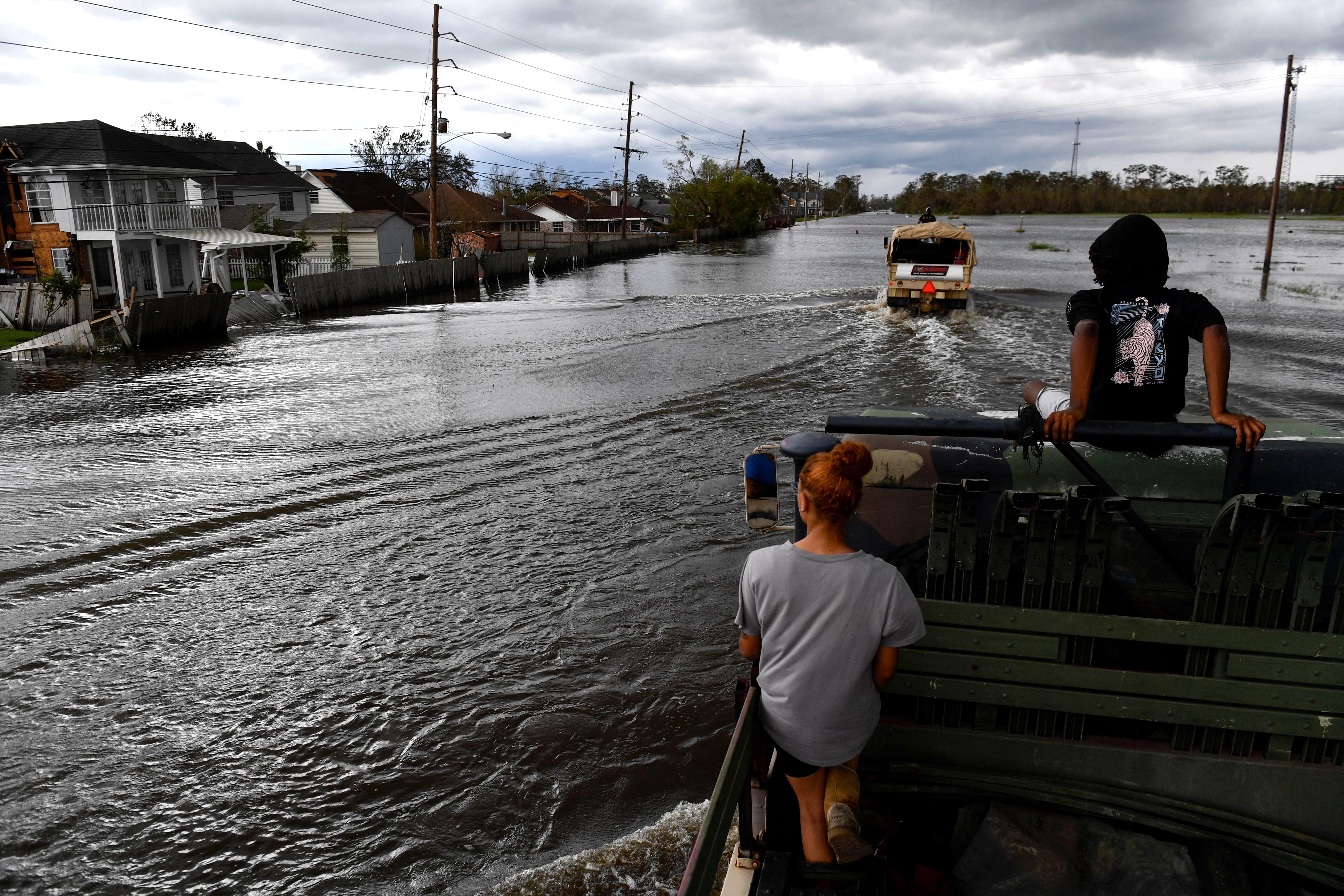 Two people in the back of a hi water truck combing through floodwaters.