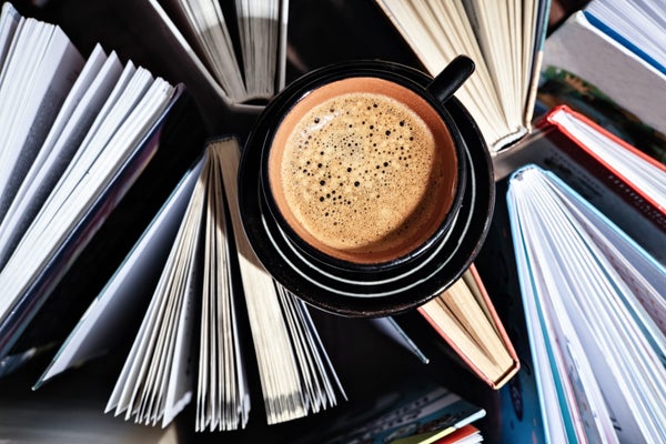 Many open books top view with cup of coffee sitting on top