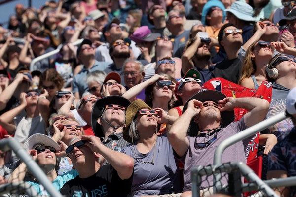 Crowd of people with Eclipse glasses looking up.