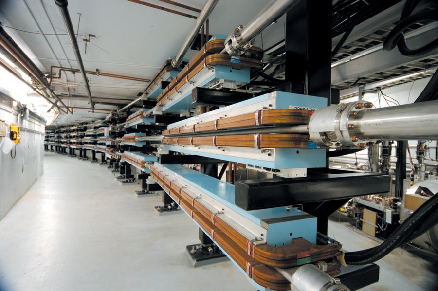 A curved hallway with industrial equipment lining the righthand wall. 